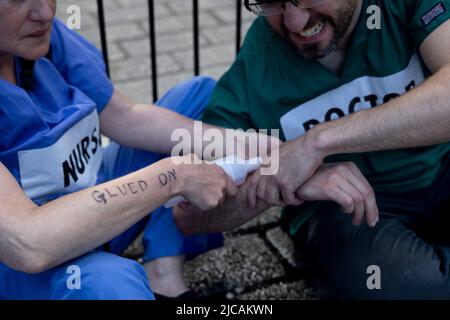 Londra, Regno Unito. 11th giugno 2022. I dimostranti professionisti del settore sanitario si vedono disincollarsi le mani. Gli operatori sanitari si sono incollati fuori Downing Street per protestare contro il sostegno finanziario e normativo dei combustibili fossili da parte del governo britannico. Credit: SOPA Images Limited/Alamy Live News Foto Stock