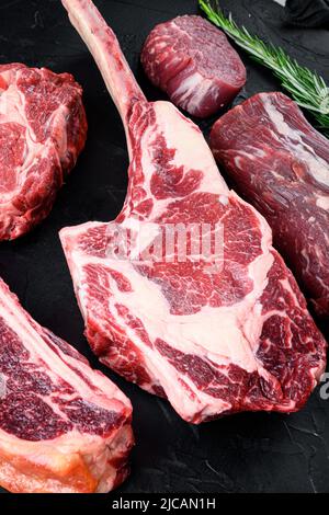 Bistecche di carne Black Angus prime crude, taglio Tomahawk, su sfondo di pietra nera Foto Stock