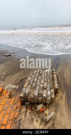 Il cambiamento climatico ha creato l'erosione della spiaggia e parte del muro di mare è caduto nella spiaggia diretta per l'oceano. Foto Stock