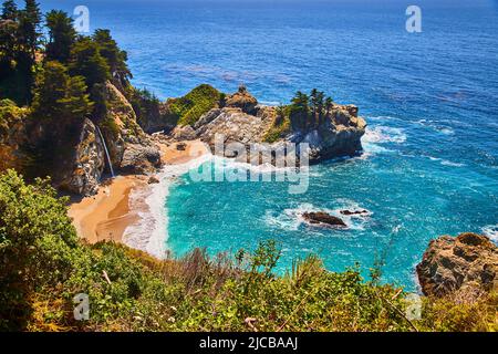 Piccola baia sull'oceano circondata da scogliere, cascate e spiagge sabbiose Foto Stock