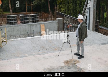 Opere geodetiche. Ingegnere Surveyor che utilizza attrezzature geodetiche in cantiere. Attrezzatura professionale per building. Lavoro come un topografo. Ottico Foto Stock