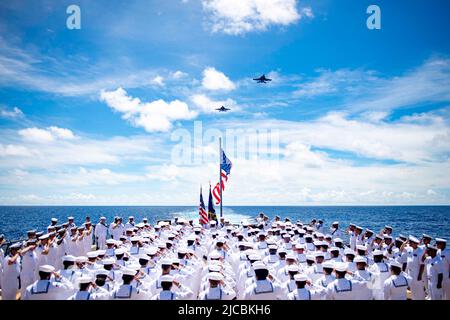 Mar delle Filippine. 4th giugno 2022. I marinai a bordo del cacciatorpediniere missilistico guidato di classe Arleigh Burke USS Spruance (DDG 111) salutano l'insegna durante l'inno nazionale mentre due EA-18G Growlers, assegnati ai 'Wizards' di Electronic Attack Squadron (VAQ) 133, conducono un volo-by durante una cerimonia tenuta in riverenza della Battaglia di Midway. Abraham Lincoln Strike Group è in fase di implementazione pianificata nell'area delle operazioni della flotta USA 7th per migliorare l'interoperabilità attraverso alleanze e partnership, fungendo da forza di risposta pronta a supportare una regione indopacifica libera e aperta. (Credito IMA Foto Stock