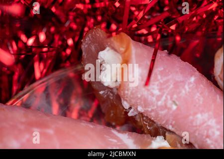 Un rotolo di carne secca e formaggio morbido su un piatto di vetro sul tavolo. Tavolo festivo. Foto Stock