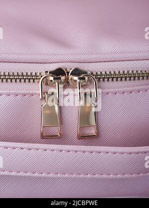 le zip in oro con zip in oro sono fissate su un oggetto in pelle rosa, in primo piano Foto Stock