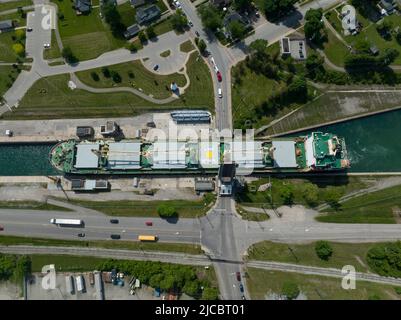 Una vista aerea dall'alto e dall'alto verso il basso di una nave portarinfuse che passa attraverso uno stretto canale urbano in corrispondenza di un ponte levatoio che attraversa il giorno. Foto Stock