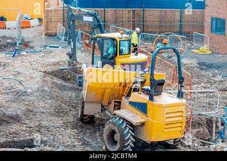 Impianti di costruzione e macchinari. Dumper ed escavatore che lavorano su cantiere di nuove case Foto Stock