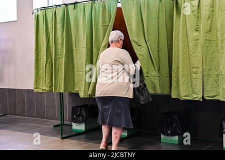 12 giugno 2022, Cours la Ville, Auvergne Rhone Alpes, Francia: Una donna entra in una cabina di voto. Il popolo francese è chiamato a votare per il primo turno delle elezioni legislative che eleggeranno i deputati che siederanno all'Assemblea nazionale. Qui, in un seggio di Cours-la-Ville la Domenica mattina. (Credit Image: © Adrien Fillon/ZUMA Press Wire) Foto Stock