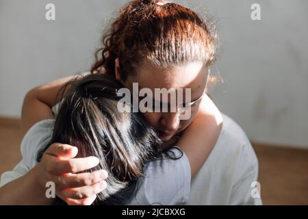 Ritratto di famiglia abusata. Giovane donna triste che tiene la ragazza, consolante. Figlia spaventata che abbraccia la madre. Violenza domestica. Foto Stock