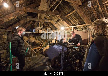 Uomo che parla con i turisti in una Blackhouse a Gearrannan vicino Carloway, Isola di Lewis, Ebridi esterne, Scozia, Regno Unito Foto Stock