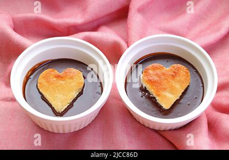 Primo piano di due dolci Mousse al cioccolato decorati con dolci a forma di cuore in chiffon Foto Stock