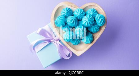 Scatola regalo blu con nastro viola e meringa del piatto del cuore Foto Stock