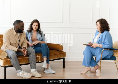 Sottolineato infelice millenario caucasico e African American coppia hanno problemi di relazione. Diverse coppie in lotta mentre si visita professionale Foto Stock