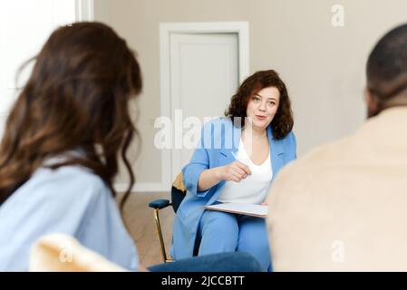 Una psicologa di famiglia femminile parla a una coppia diversa del loro rapporto. Uno psichiatra aiuta una giovane famiglia a non divorziare. Foto Stock