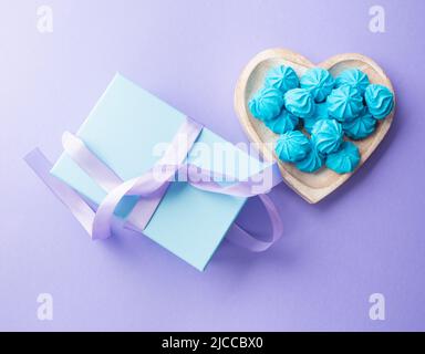 Scatola regalo blu con nastro viola e meringa del piatto del cuore Foto Stock