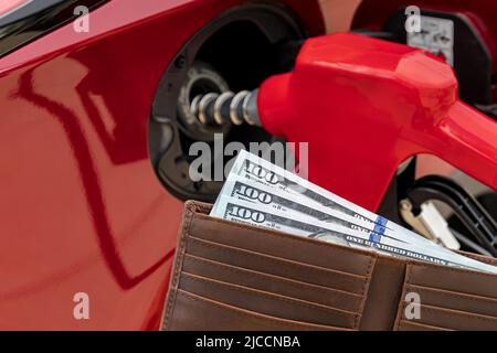 Rifornimento auto al distributore di benzina con denaro in contanti nel portafoglio. Concetto di aumento del prezzo del gas, di imposta e di carenza di carburante. Foto Stock