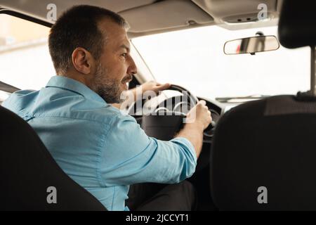 Uomo di età media che guida seduto in modalità New Auto, Vista posteriore Foto Stock