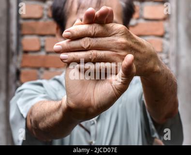 Rafforzamento dell'esercizio per i muscoli del braccio di un paziente maschile anziano asiatico con spasmo muscolare. Foto Stock