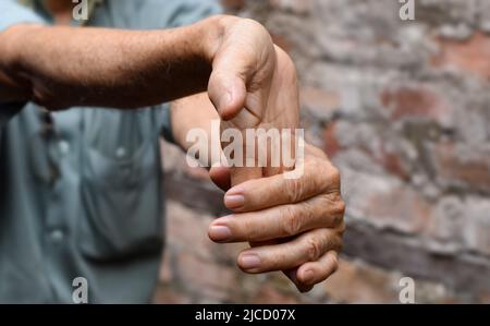 Rafforzamento dell'esercizio per i muscoli del braccio di un paziente maschile anziano asiatico con spasmo muscolare. Foto Stock