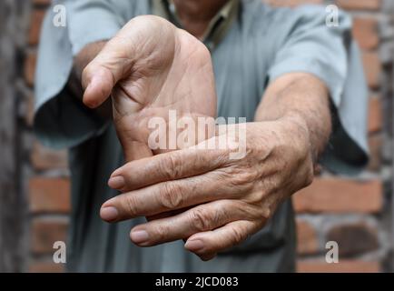 Rafforzamento dell'esercizio per i muscoli del braccio di un paziente maschile anziano asiatico con spasmo muscolare. Foto Stock