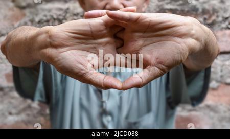 Rafforzamento dell'esercizio per i muscoli del braccio di un paziente maschile anziano asiatico con spasmo muscolare. Foto Stock