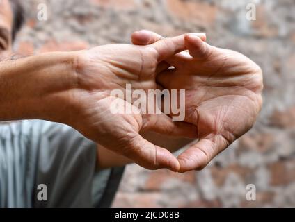 Rafforzamento dell'esercizio per i muscoli del braccio di un paziente maschile anziano asiatico con spasmo muscolare. Foto Stock