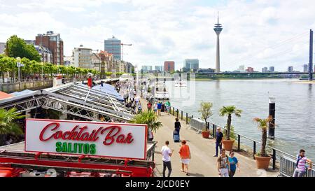 La passeggiata sul fiume Reno a Düsseldorf/Germania in una giornata estiva. Il punto di riferimento della Torre del Reno è visibile sullo sfondo. Foto Stock