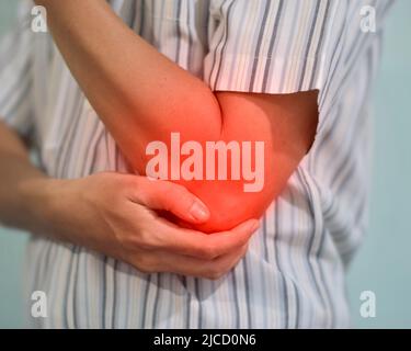 Dolore nel gomito del giovane uomo del sud-est asiatico. Concetto di dolore al gomito, artrite reumatoide e problemi al braccio. Foto Stock