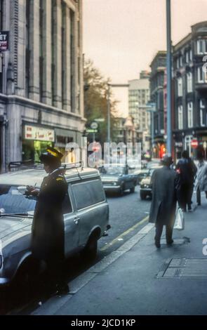 1970s immagine di archivio di un guardiano del traffico che scrive un biglietto a Wardour Street, Soho, Londra. Foto Stock