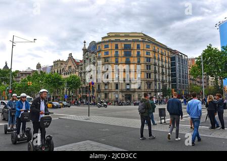 Barcellona, Spagna - 5 maggio 2018: Le persone cavalcano scooter elettrici in Segway attraverso l'incrocio di Passeig de Gràcia, un'area commerciale di alto livello. Casa Battlo Foto Stock