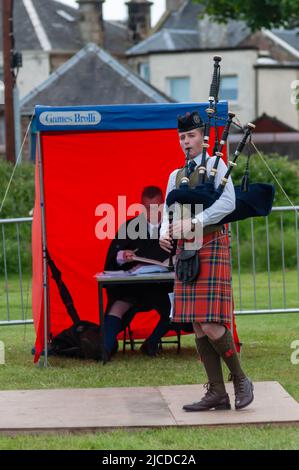 Ardrossan, Scozia, Regno Unito. 12th giugno 2022. Solo piping concorrenza al Ardrossan Highland Games come fa un ritorno dopo un due anni di assenza a causa della pandemia di Covid-19. I giochi celebrano la cultura scozzese con gare di pipe band solisti, balli highland e tradizionali eventi di pesi massimi. Credit: SKULLY/Alamy Live News Foto Stock