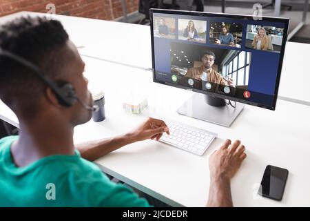 Vista ad alto angolo dell'uomo d'affari afro-americano che discute in linea con i colleghi sopra il calcolatore Foto Stock