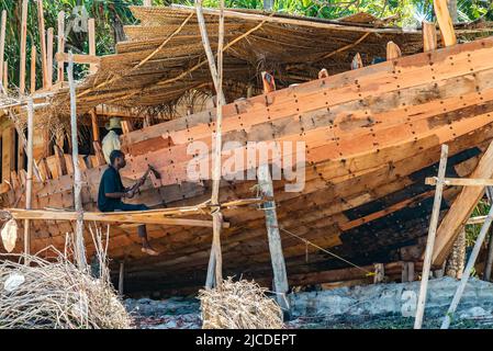 Nungwi, Zanzibar, Tanzania, 19 DICEMBRE 2021 - uomo che costruisce a mano una tradizionale barca a vela in legno su una spiaggia Foto Stock