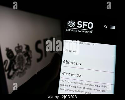 Persona che detiene il cellulare con il sito web dell'agenzia britannica Serious Fraud Office (OFS) sullo schermo di fronte al logo. Concentrarsi sul centro del display del telefono. Foto Stock
