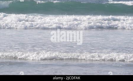 Le grandi onde blu dell'oceano si infrangono sulla spiaggia, la costa pacifica della California, gli Stati Uniti. Schiuma di acqua di mare e sabbia bianca. Estate estetica a terra. Surf vibes, stagcape vicino a Los Angeles. Cinematografia senza giunture. Foto Stock