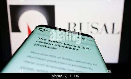 Telefono cellulare con pagina web della società russa United Company RUSAL IPJSC sullo schermo di fronte al logo aziendale. Mettere a fuoco sulla parte superiore sinistra del display del telefono. Foto Stock