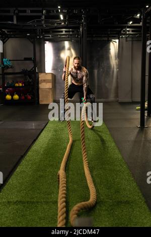 Corda magazzino fitness uomo verde erba palestra muscolare giovane, per la forza forte da attività fisica sana, muscolare persona. Croce Foto Stock