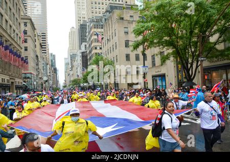 I partecipanti sono visti tenere una bandiera portoricana enorme sulla Fifth Avenue a New York City durante la National Puerto Rican Day Parade, di ritorno dopo un Foto Stock