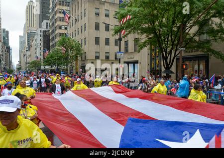 I partecipanti sono visti tenere una bandiera portoricana enorme sulla Fifth Avenue a New York City durante la National Puerto Rican Day Parade, di ritorno dopo un Foto Stock