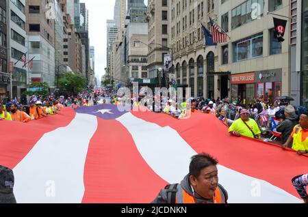 I partecipanti sono visti tenere una bandiera portoricana enorme sulla Fifth Avenue a New York City durante la National Puerto Rican Day Parade, di ritorno dopo un Foto Stock