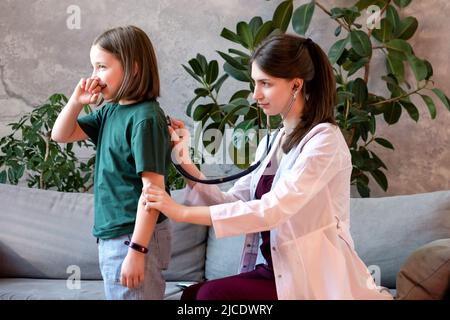 Esame dei polmoni di auscultazione con stetoscopio. Bambino ragazza visita medico per il controllo regolare. Donna amichevole pediatra in Pediatric Medical Office con Foto Stock