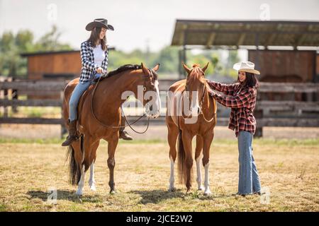 La convivenza e l'amicizia di due ragazze e due cavalli che vanno per un giro estivo. Foto Stock