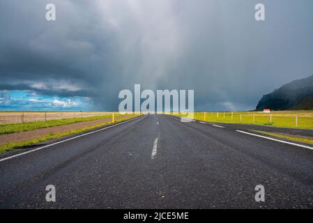 Vista panoramica della strada vuota nella valle tra verde paesaggio contro cielo nuvoloso Foto Stock