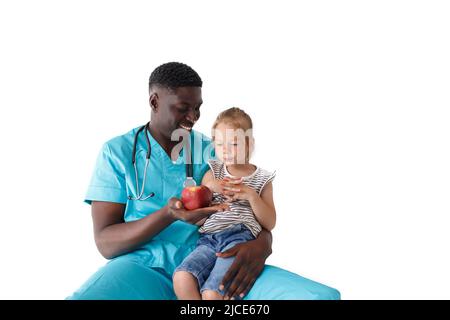 Il medico afro-americano dei bambini dice ad una bambina circa nutrizione adeguata che tiene una mela nelle sue mani Foto Stock