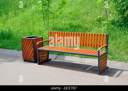 Una panca vuota nel parco vicino al sentiero e un cestino. Foto Stock