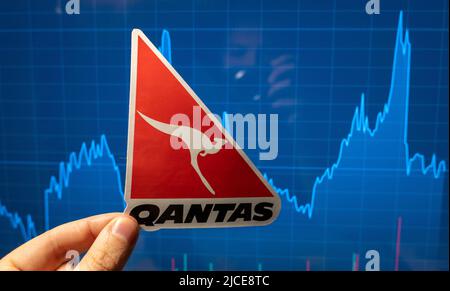 10 novembre 2021, Sydney, Australia. L'emblema della compagnia aerea Qantas sullo sfondo di un grafico dei prezzi azionari. Foto Stock