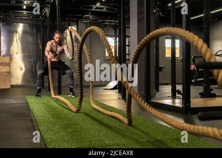 Corda magazzino fitness uomo verde erba palestra muscolare giovane, per la forza forte da attività fisica sana, muscolare persona. Croce Foto Stock