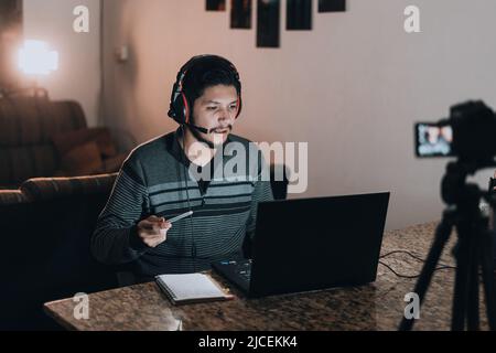 Uomo che insegna classi virtuali con un computer e una macchina fotografica di fronte a lui Foto Stock