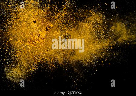 Esplosione, schizzi di curcuma su sfondo nero. India Seasoning. La polvere arancione della radice curmerica. Foto Stock