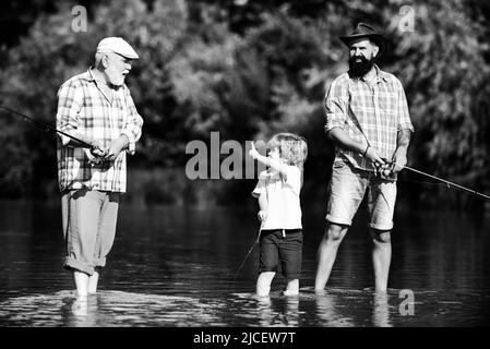 Il ragazzino pesca a mosca nel fiume con il padre e il nonno. Foto Stock