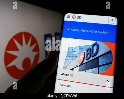 Persona che detiene il cellulare con il sito web della società medica statunitense Becton, Dickinson e Co (BD) sullo schermo con il logo. Concentrarsi sul centro del display del telefono. Foto Stock